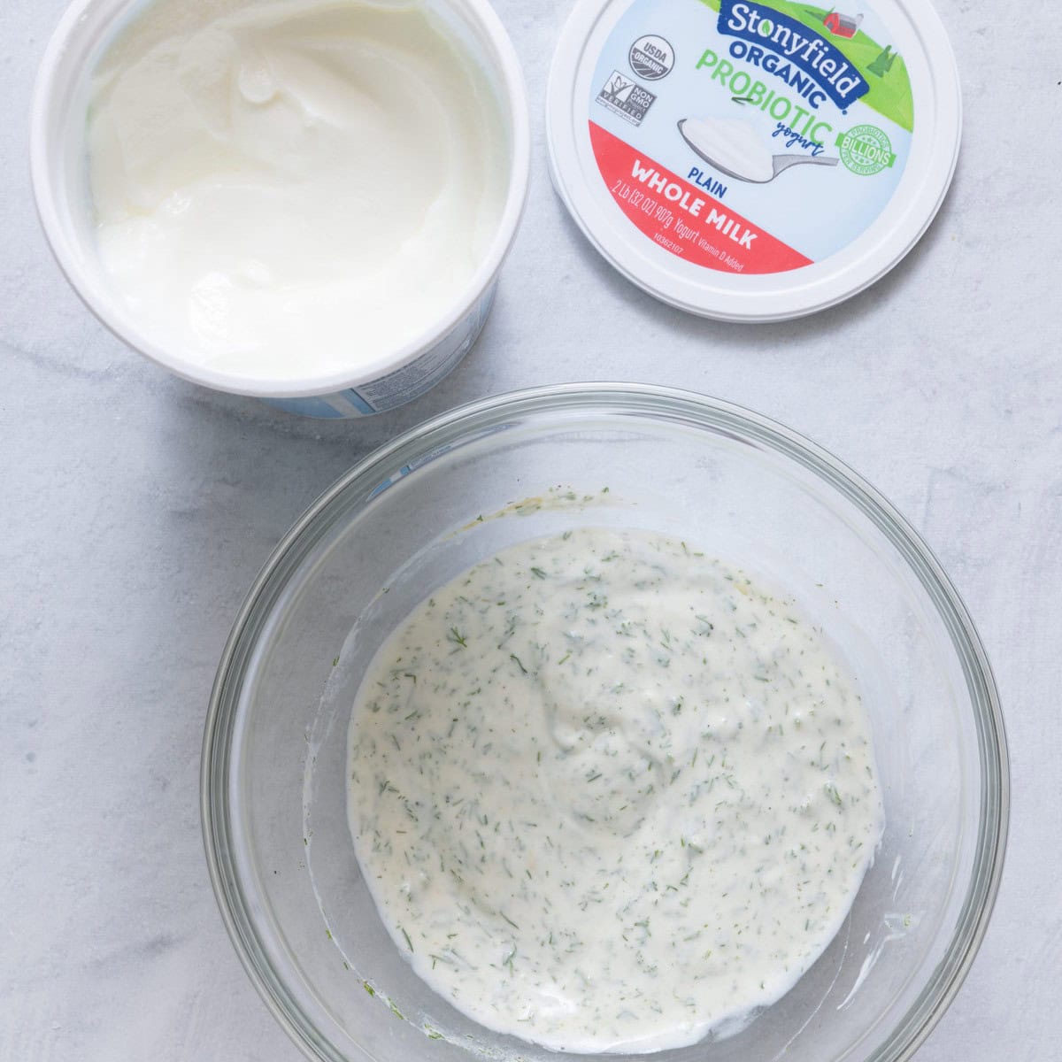 Bowl of Stonyfield yogurt, lemon juice, dill, dijon, salt and pepper after mixing.