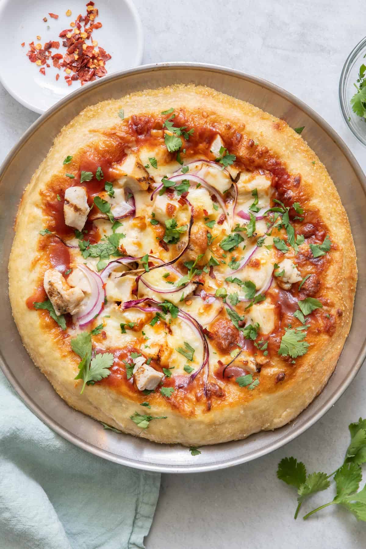 Baked pizza on baking pan with chunks of chicken and sliced red onions.