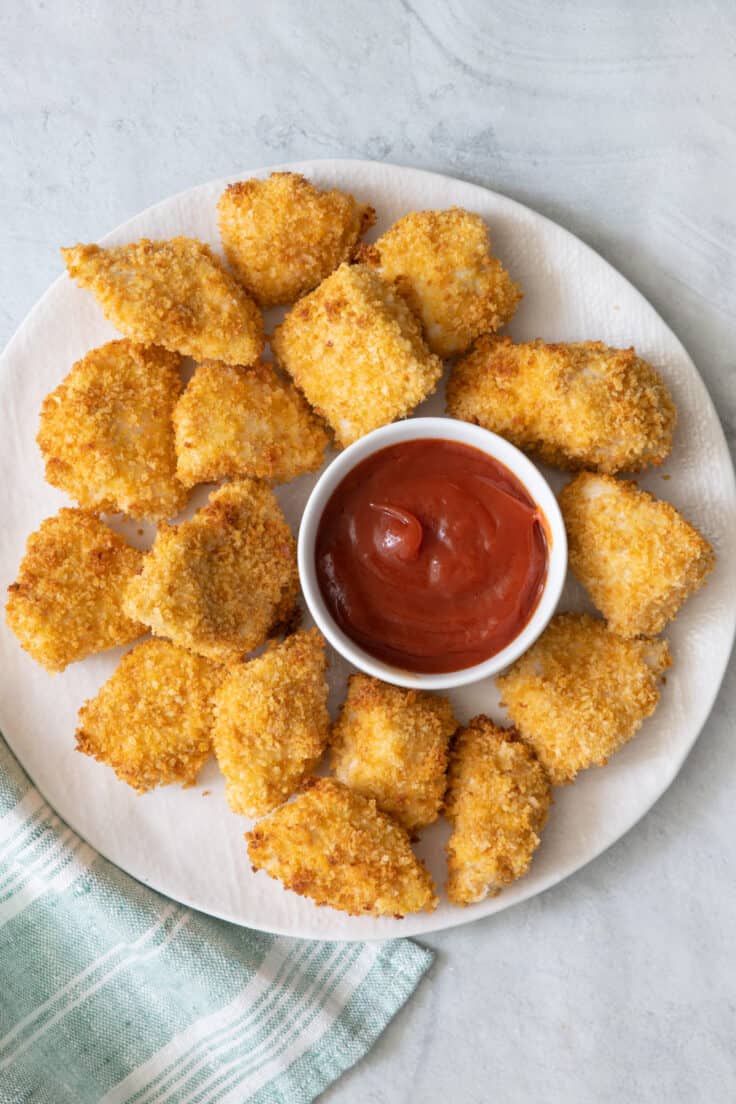 Chicken nuggets on plate with ketchup in a small pinch bowl.