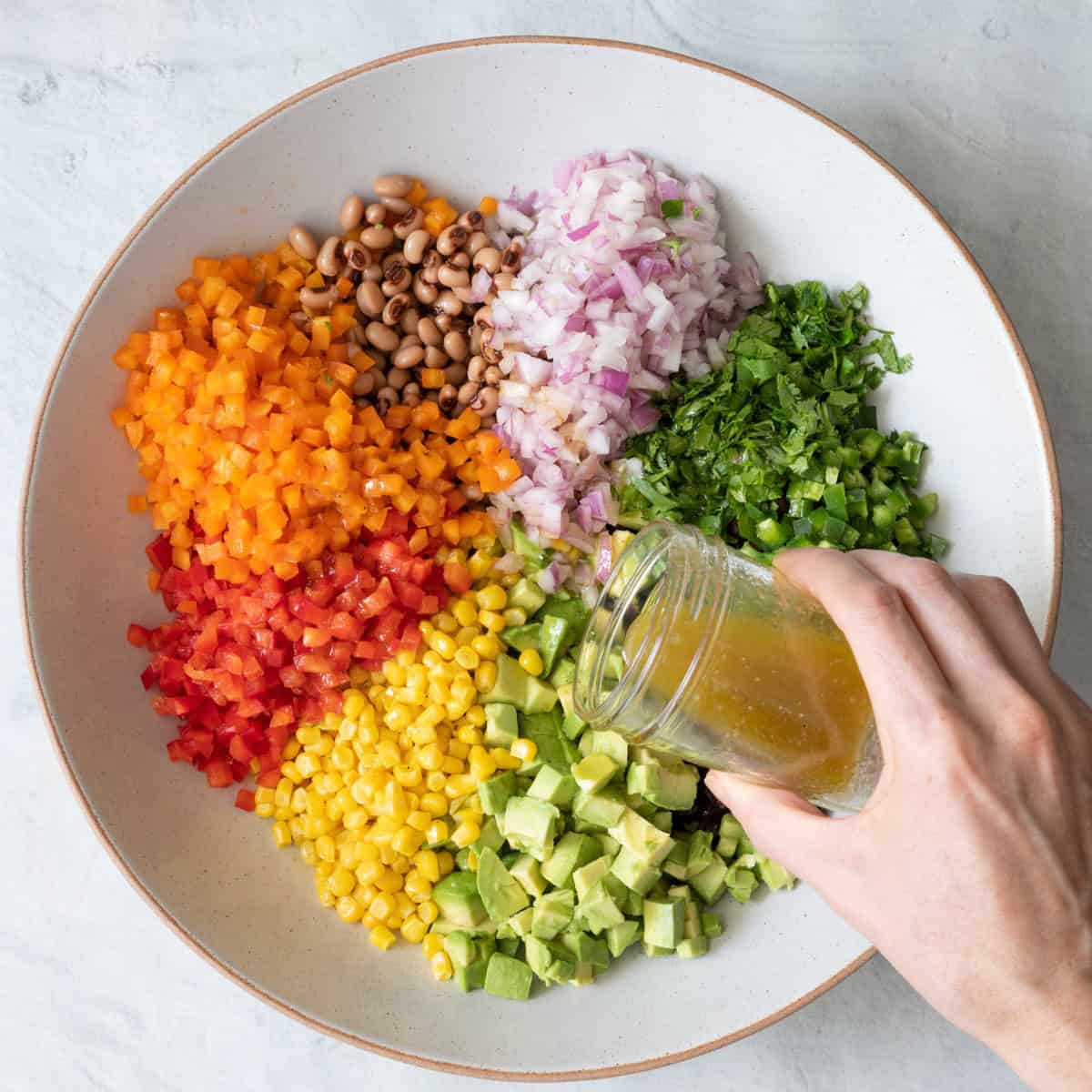 Pouring dressing on top of the salad.