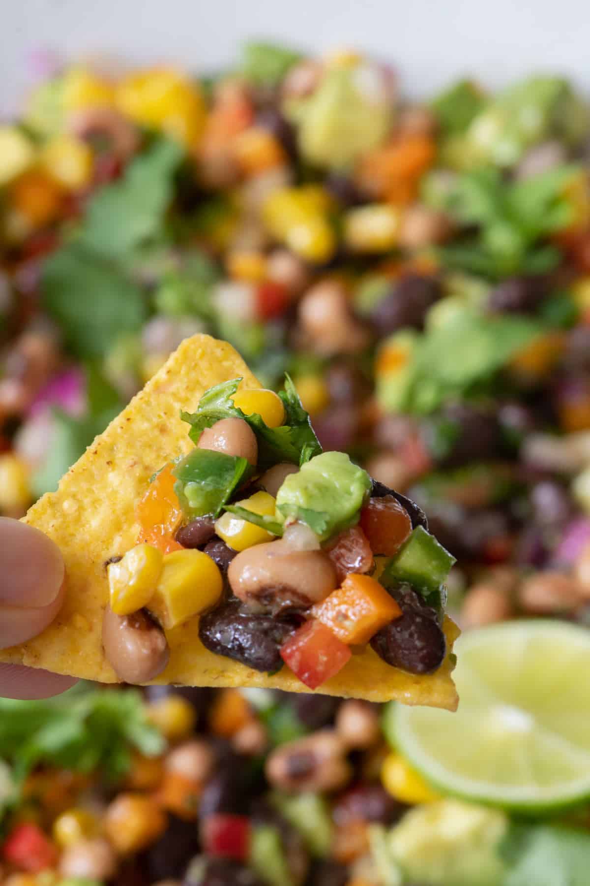 Close up of tortilla chip loaded with cowboy caviar.