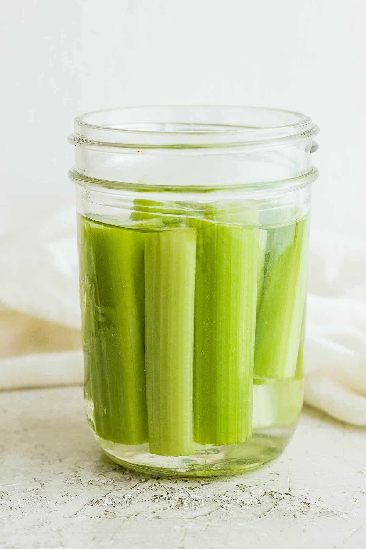 Jar of celery sticks submerged in water.