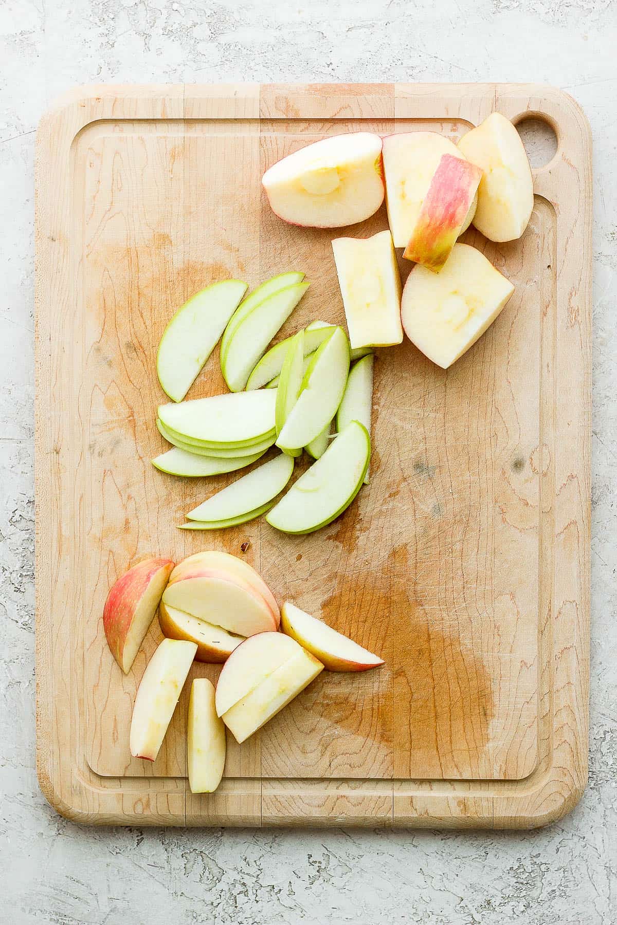 A cutting board showing 3 different types of cut and colored apples.