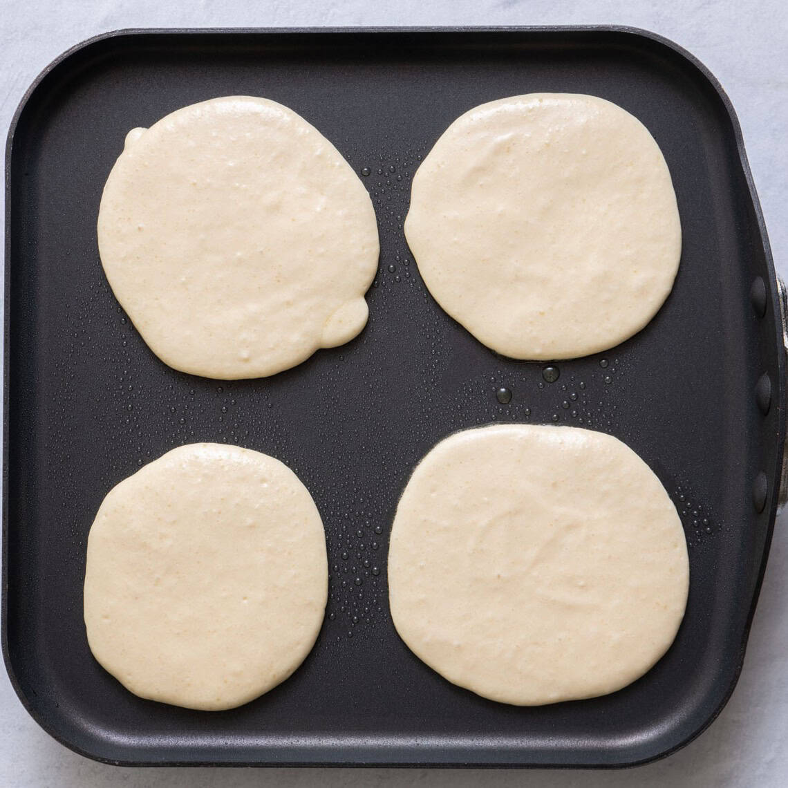Pancakes on griddle before cooked.