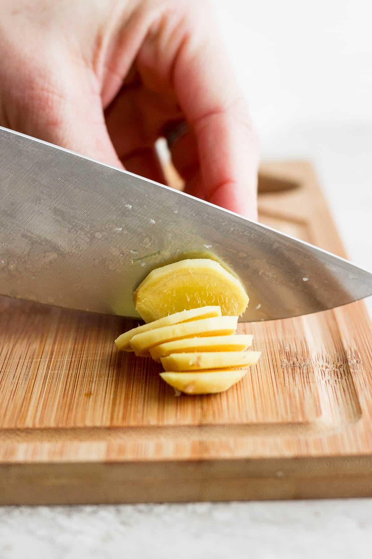Slicing ginger with a sharp knife on a cutting board