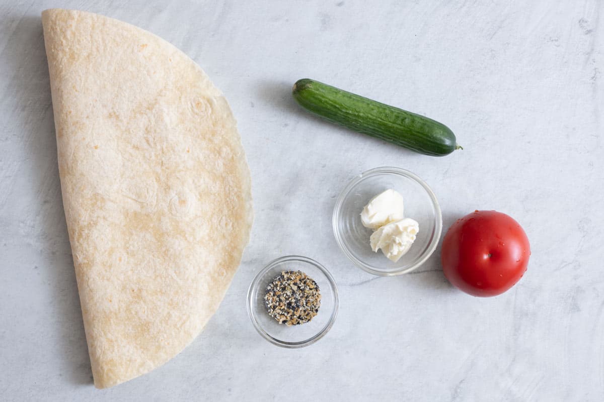 Ingredients for recipe: large tortilla shell, everything bagel seasoning, cream cheese, cucumber, and tomato.