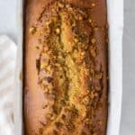 Overhead shot of pistachio bread baked in a loaf pan with parchment paper.
