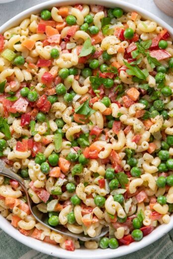 Large bowl of macaroni salad with large serving spoon inside.