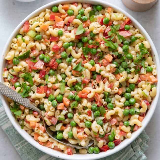 Large bowl of macaroni salad with large serving spoon inside.