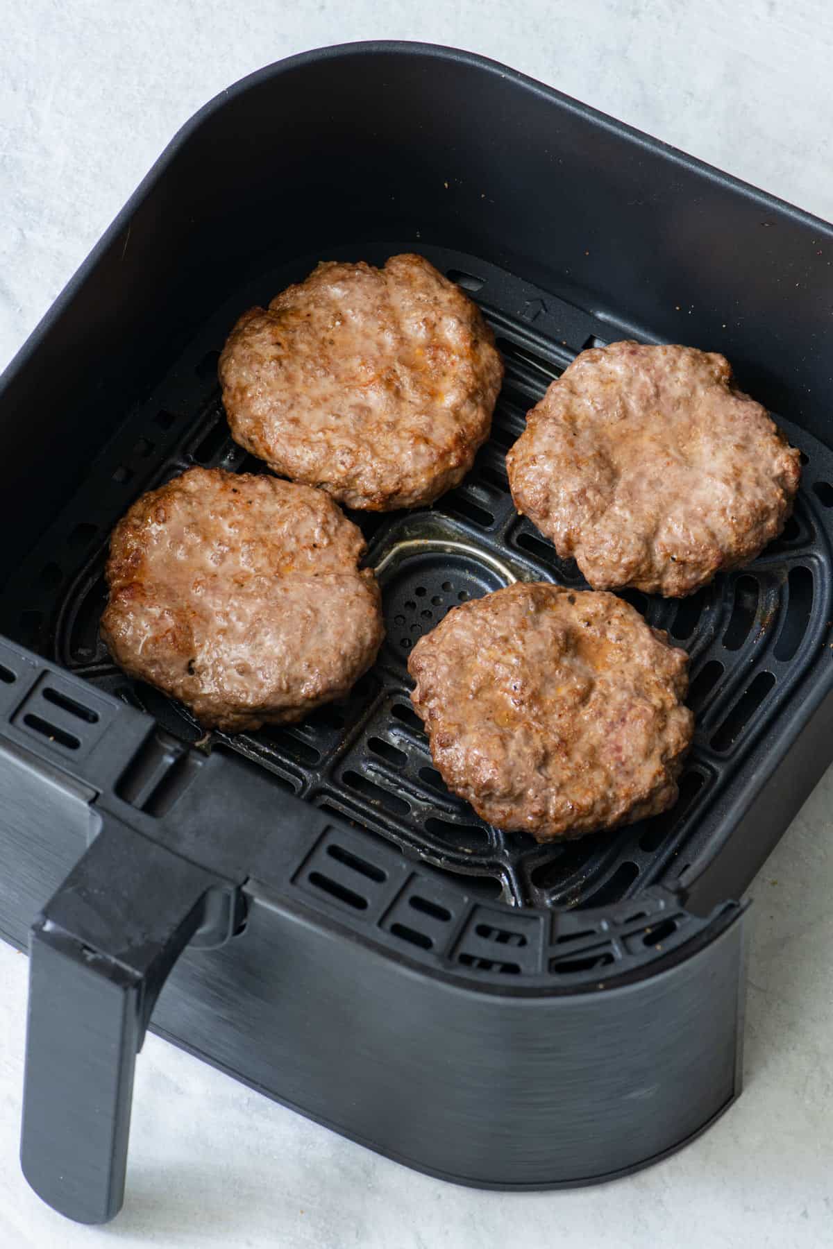 4 patties in air fryer after being cooked.