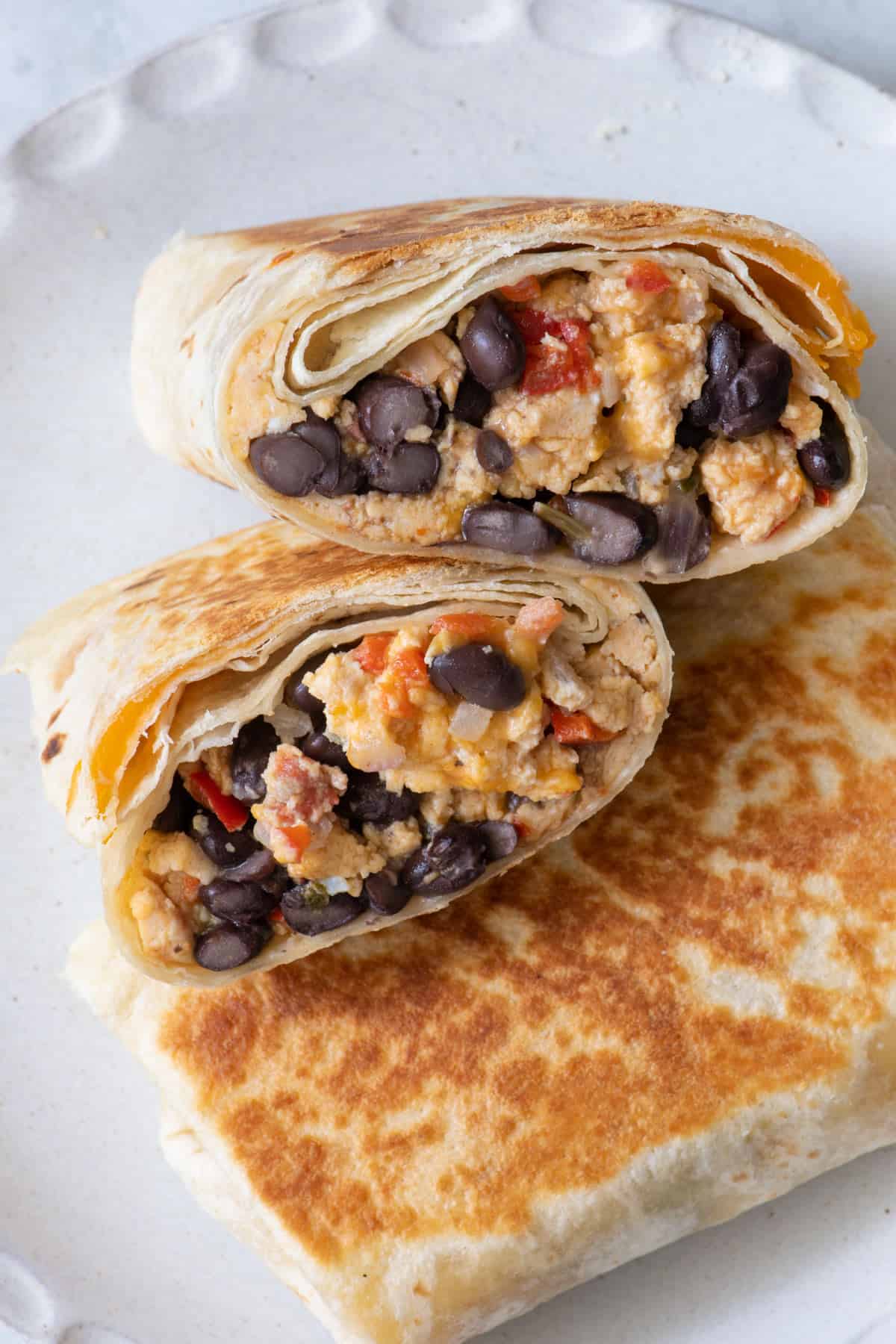 1 burrito cut in half and stacked on top of an uncut one.