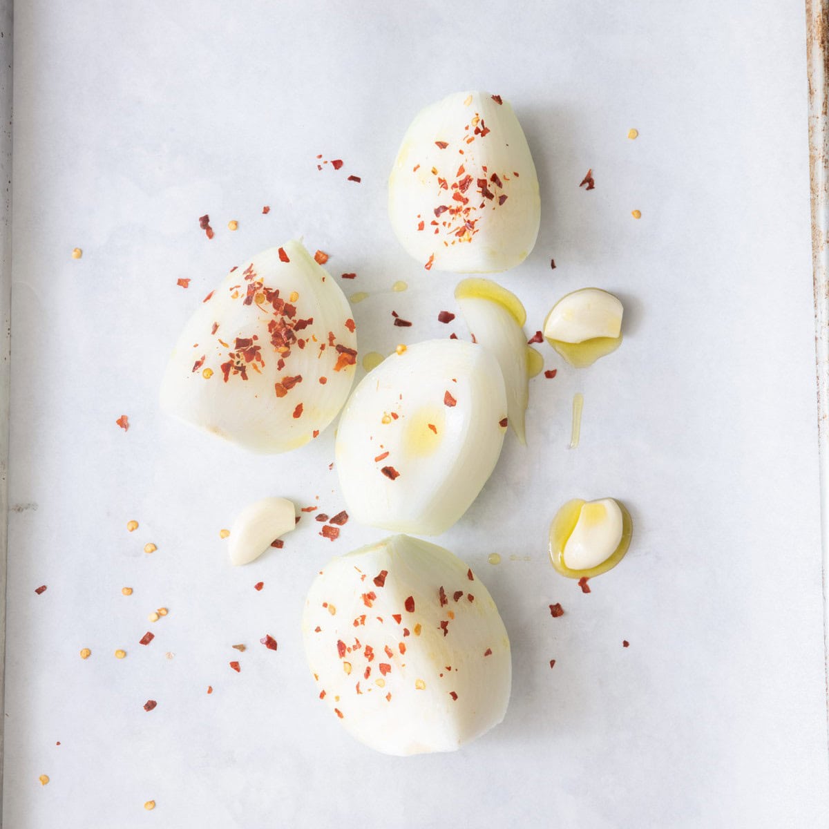 Onions and garlic on small baking dish before roasting.