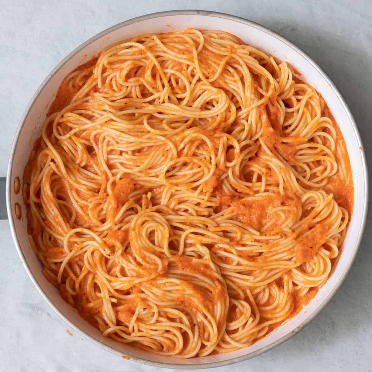 Sauce tossed with the spaghetti in skillet.