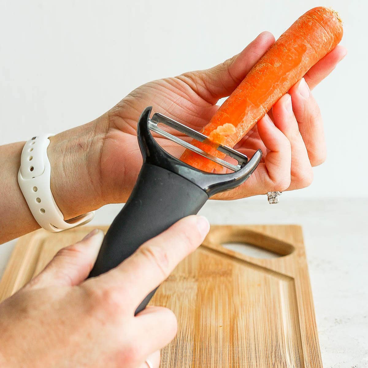 Using a y-peeler to peel a carrot before cutting it.