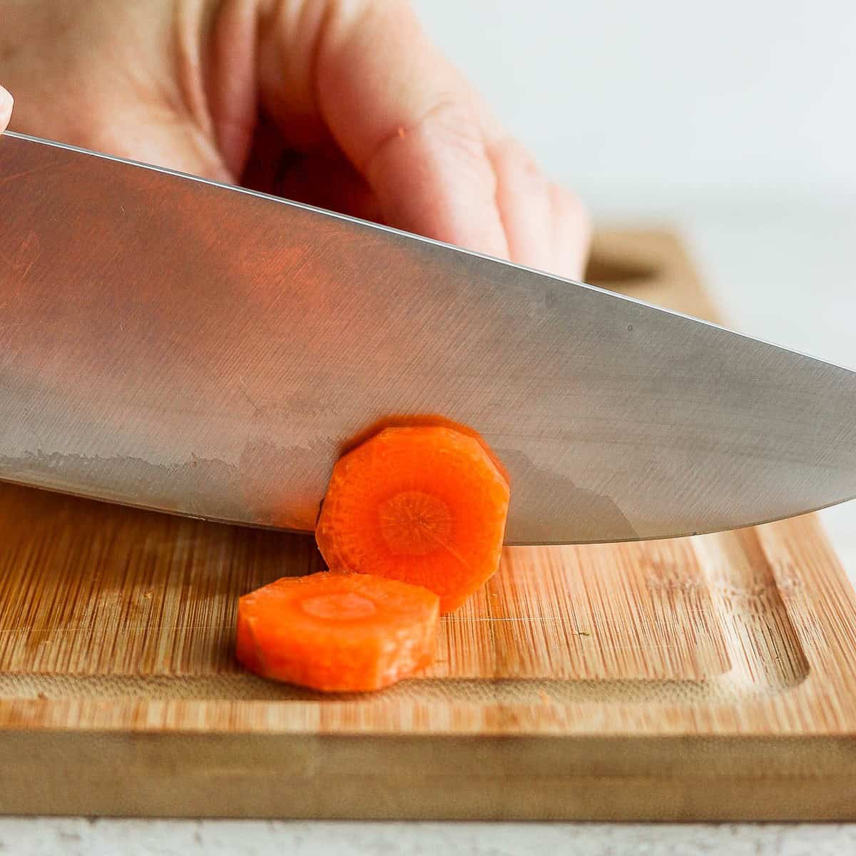 Knife slicing carrot from its bottom.