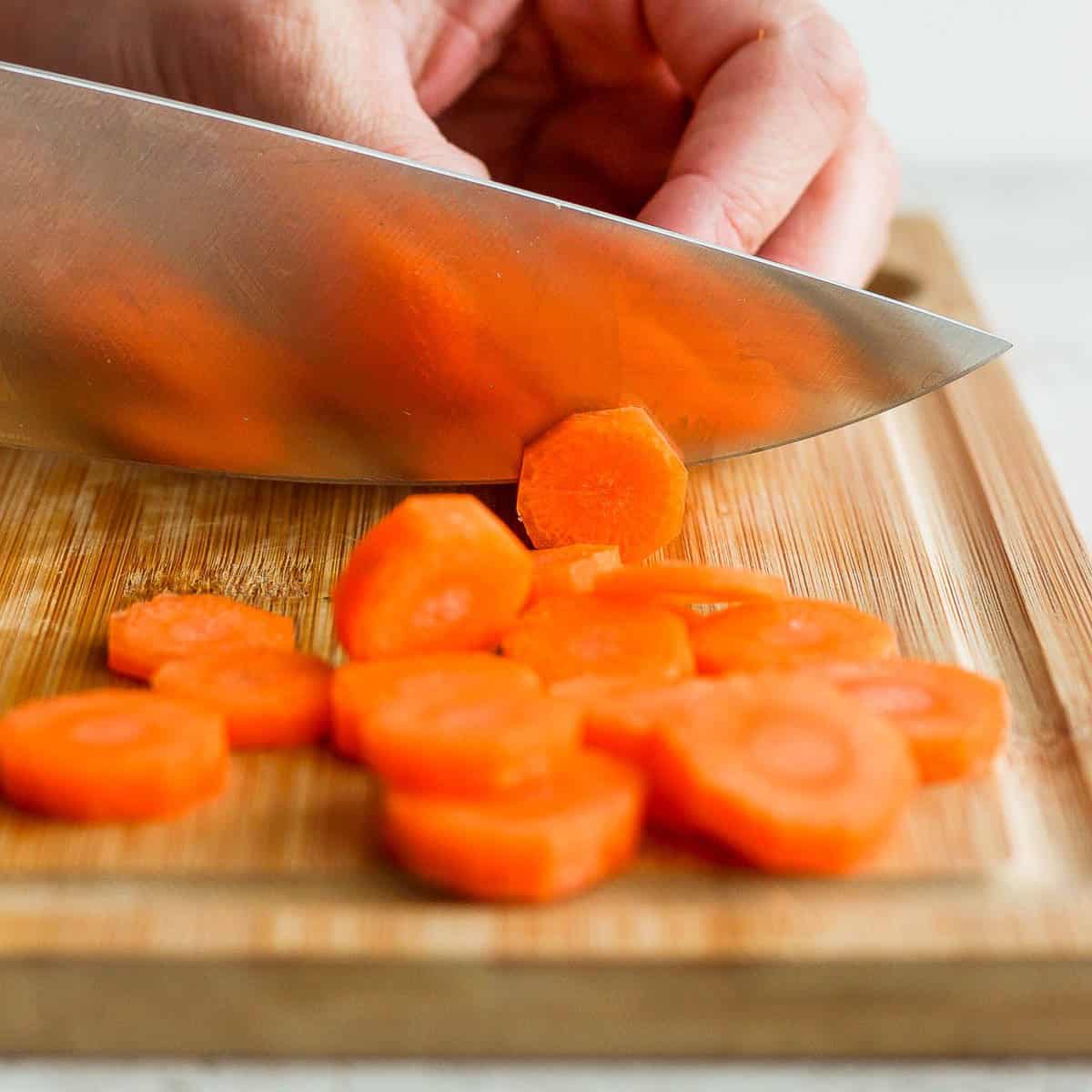 Knife slicing carrot towards its end.