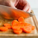 Hand cutting carrots into coins