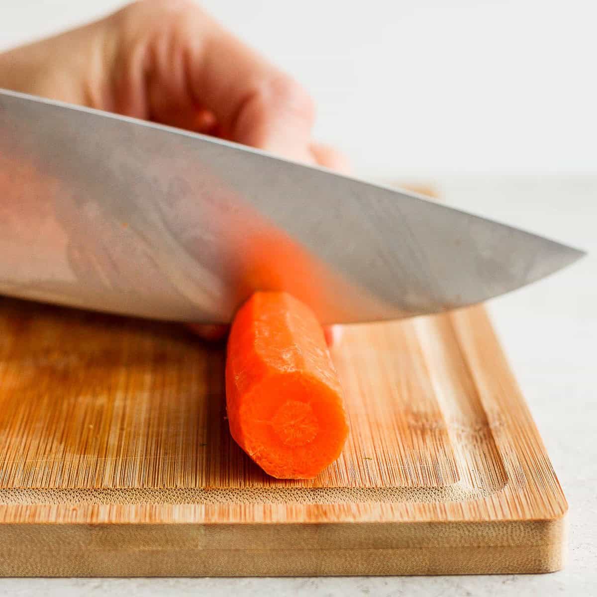 Cutting a carrot in half across its width.