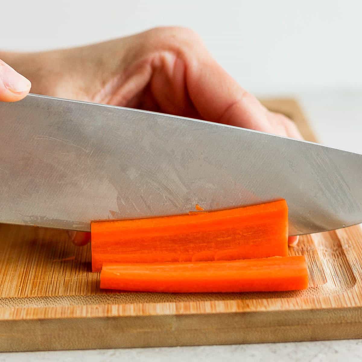 Cutting ¼ inch slabs of carrots.
