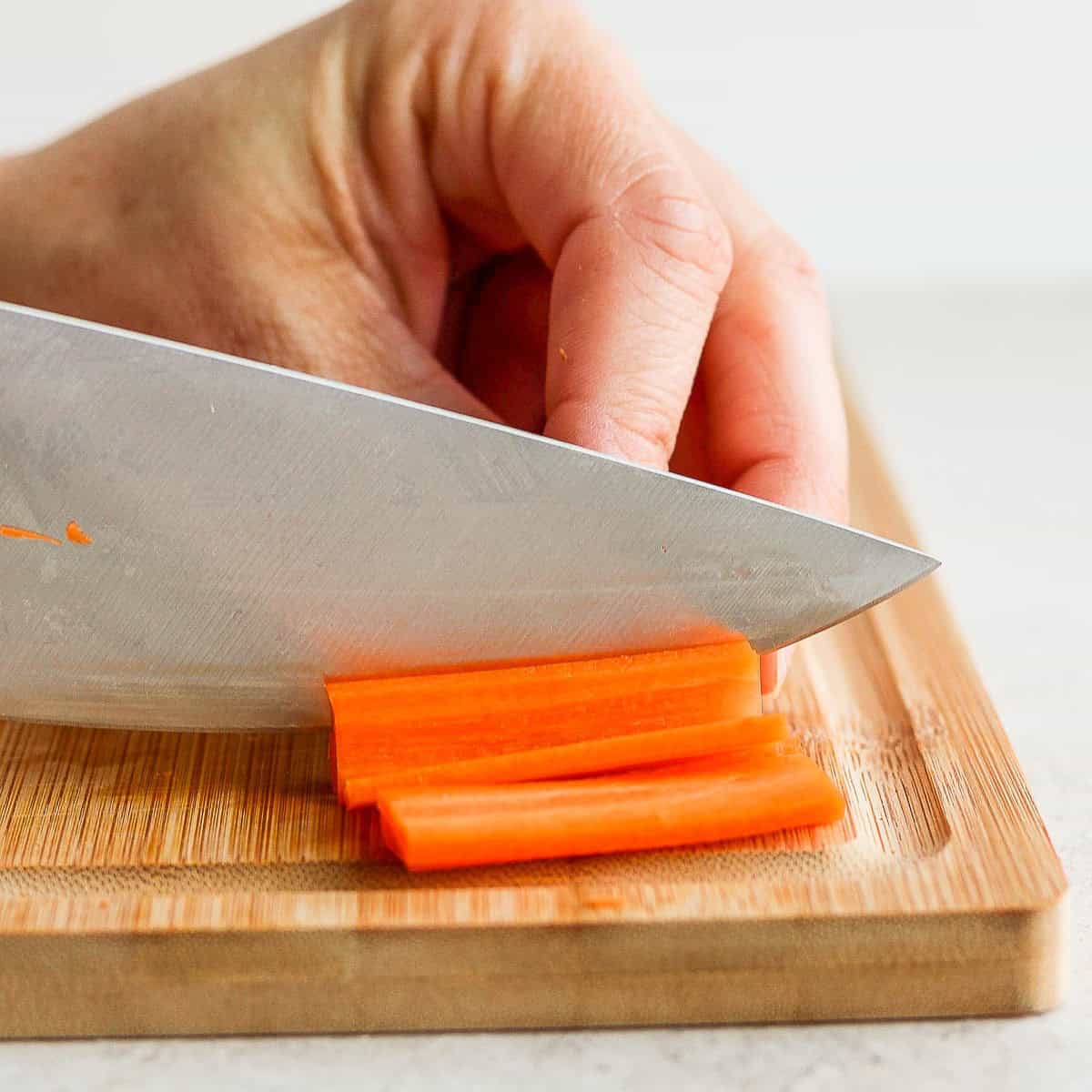 Cutting ⅛ inch slabs of carrots.