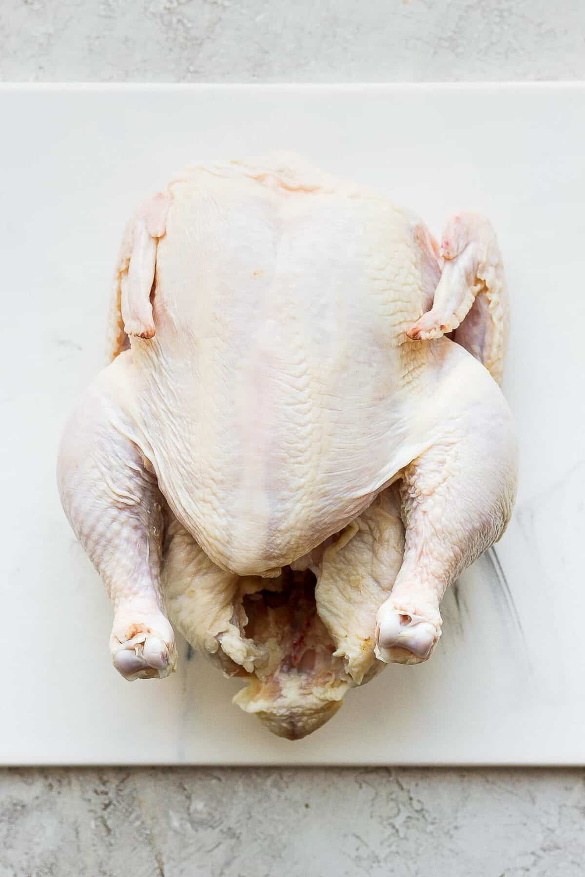 Whole chicken on cutting board.