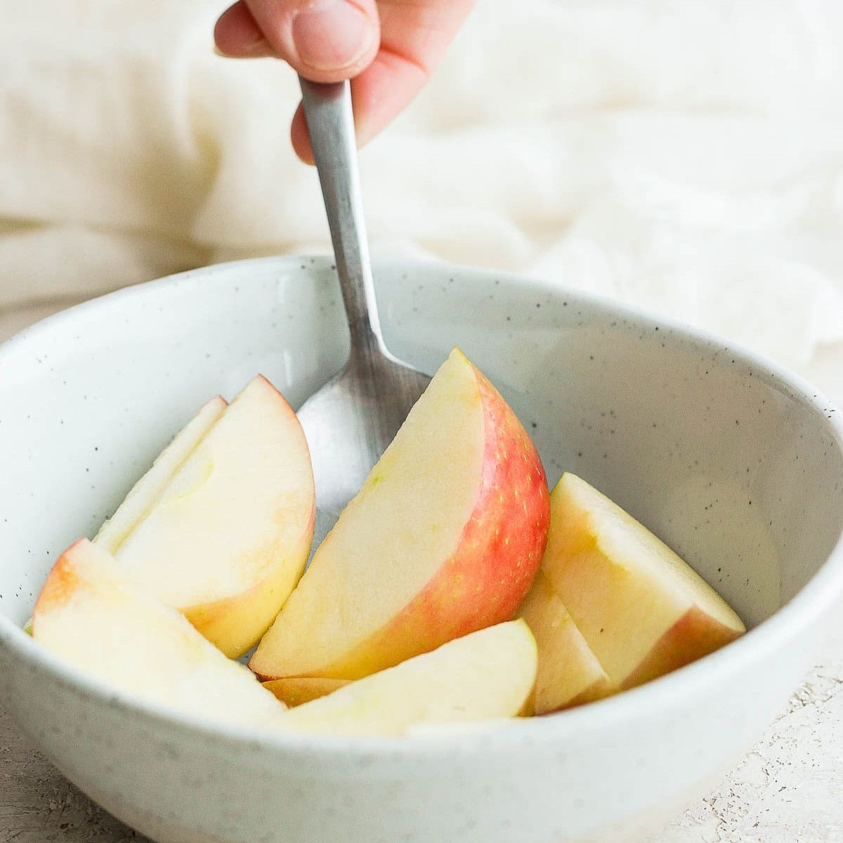 Spoon tossing apples with lemon juice.