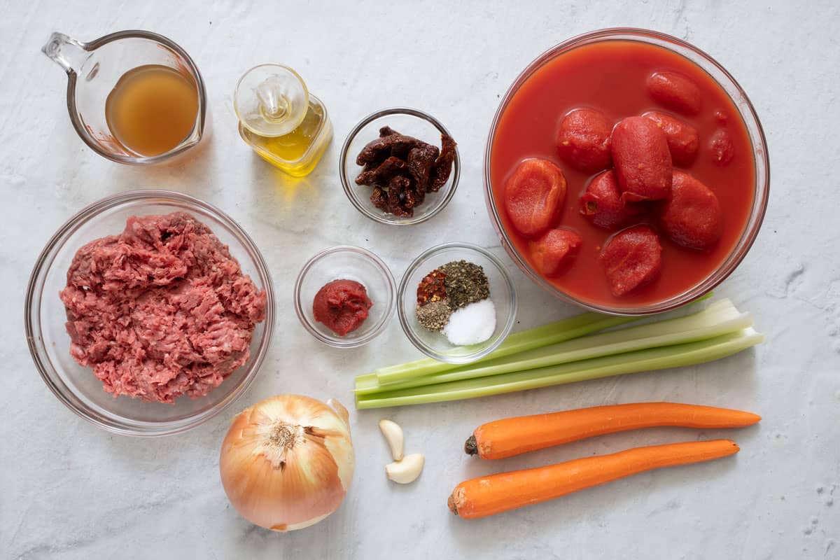 Ingredients for recipe: broth, ground beef, oil, sun-dried tomatoes, tomato paste, onion, garlic cloves, seasonings, whole tomatoes from canned, celery stalks, an carrots.