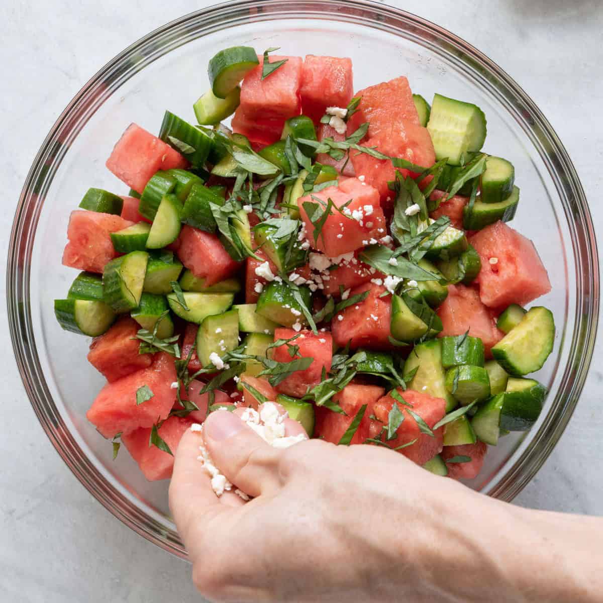 Sprinkling basil on top with feta already on.
