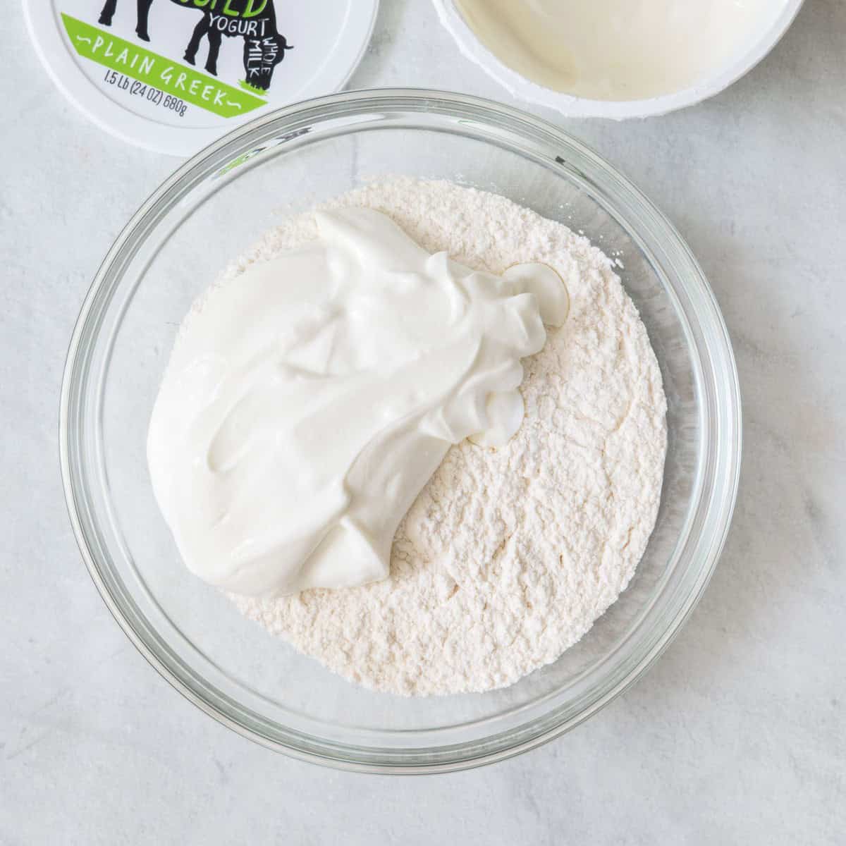 Greek yogurt on top of flour in a bowl before mixing it.