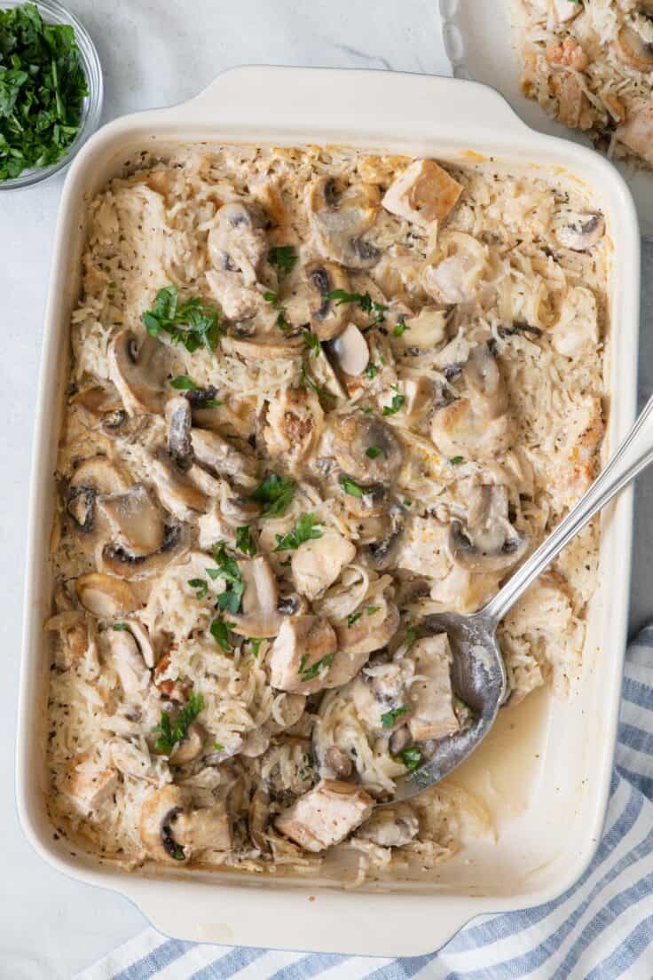 Chicken and rice casserole in a baking dish with a serving spoon place where some was scooped out.