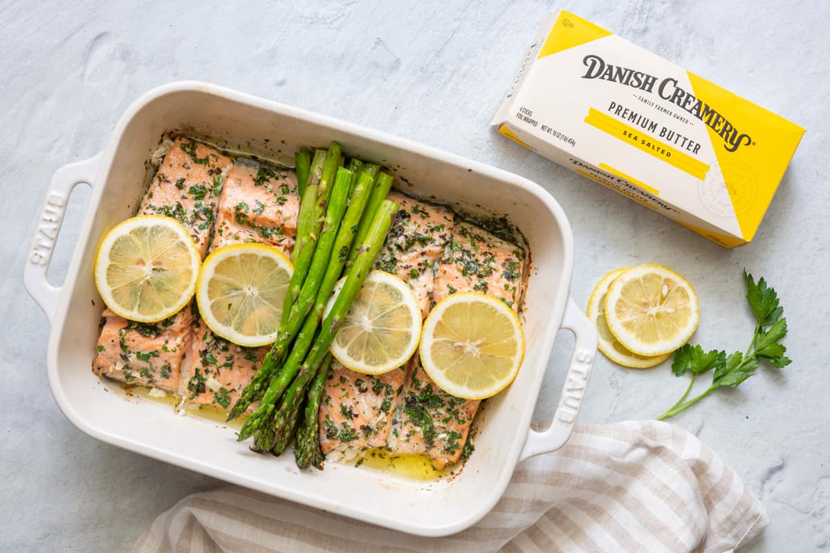 Roasted salmon in butter with asparagus made with Danish Creamery butter - package of butter next to baking dish
