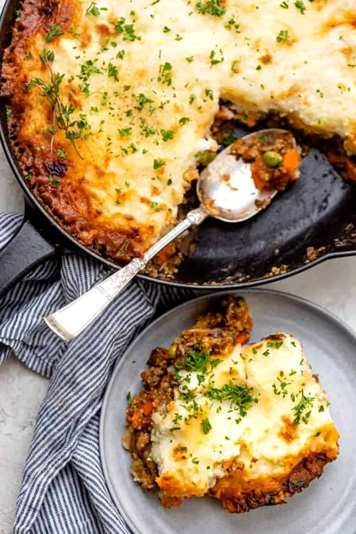 Vegetarian Shepherd's Pie in a cast iron pan with a serving dished out on a small round plate.