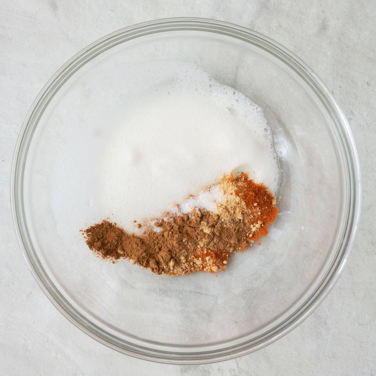 Egg in bowl after beaten, foamy with spices and salt added before combining.