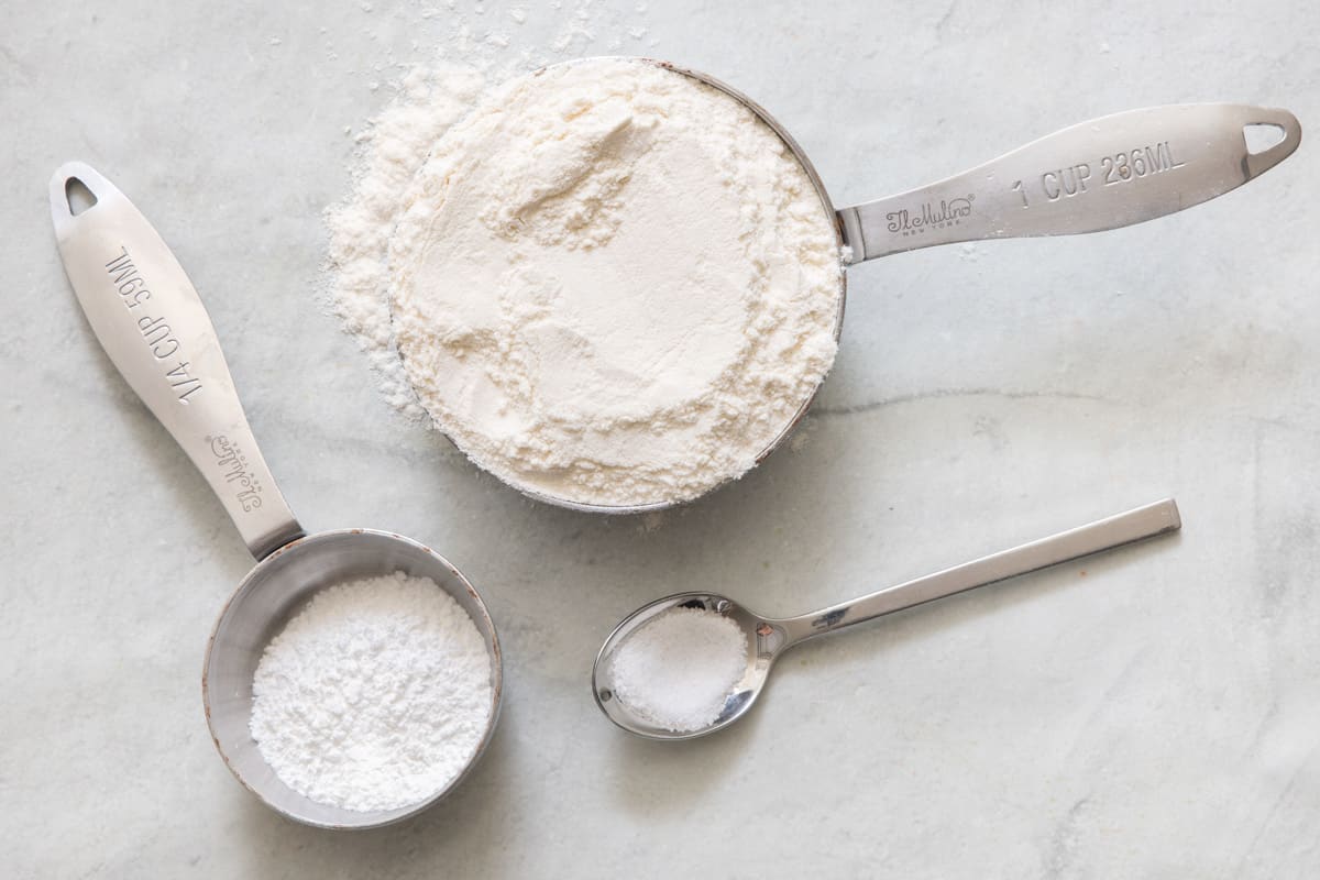 Ingredients for recipe in measuring cups and spoons: flour, baking powder, and salt.