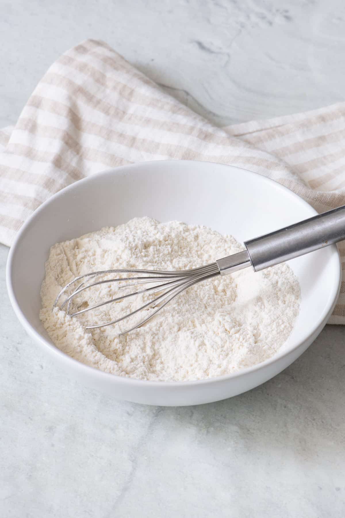 Small bowl of self rising flour with a whisk resting inside off the rim.