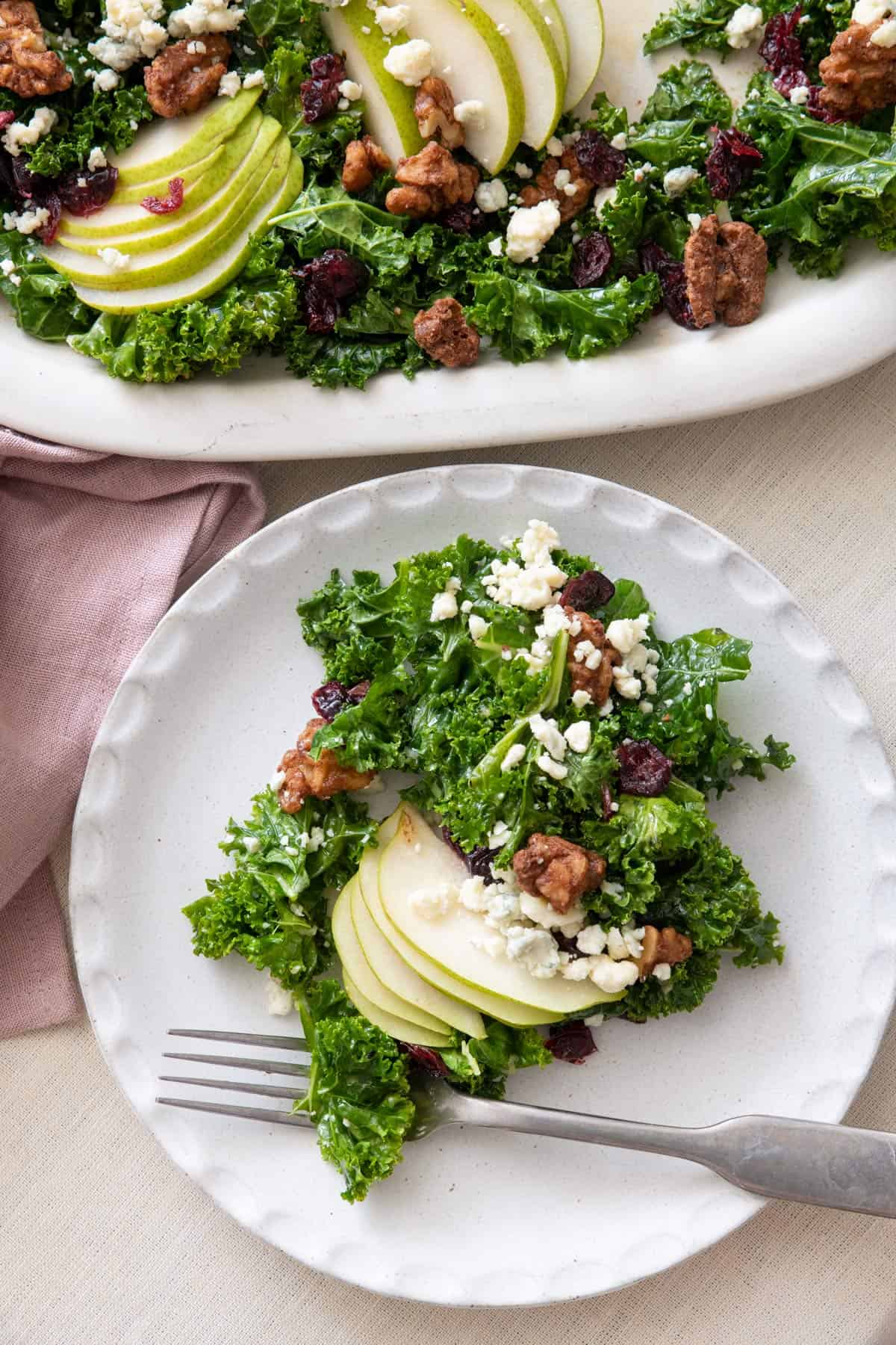 Pear salad on a small white plate with platter of salad nearby.