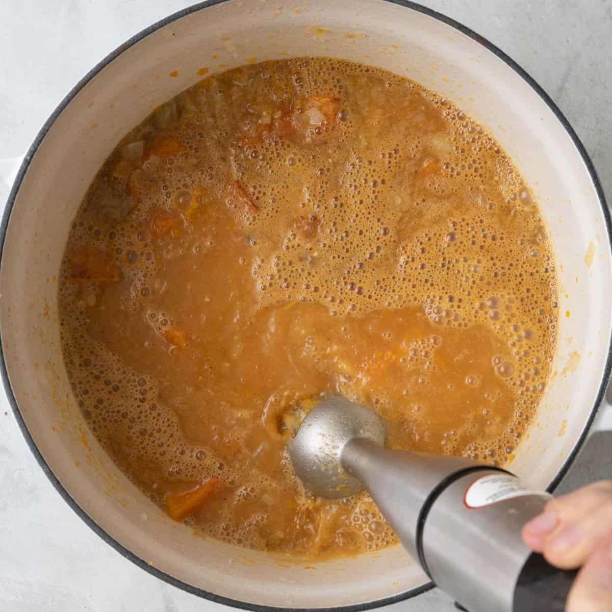 Blending soup with immersion blender.