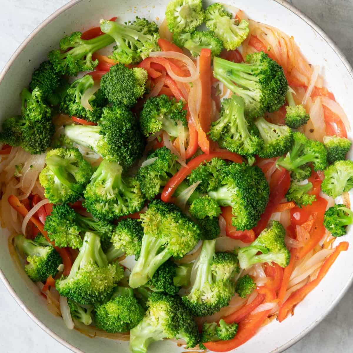 Broccoli added and steamed, shown with onions and red peppers.