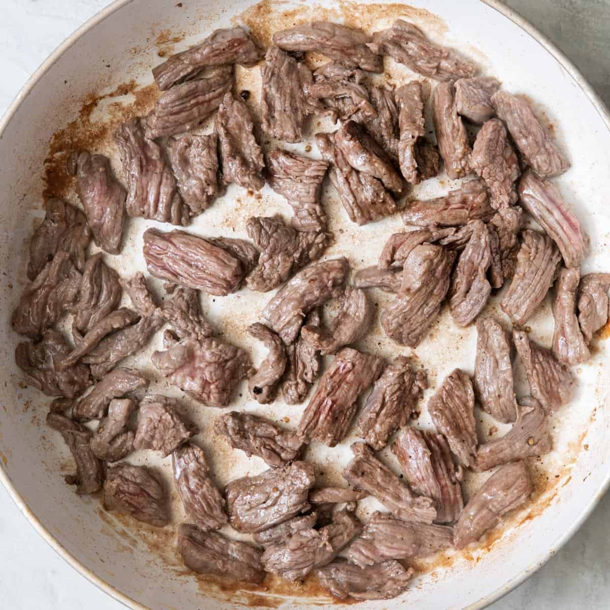 Cooked steak strips in wok without veggies.