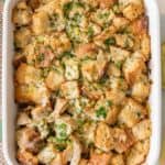 Thanksgiving stuffing in a baking dish garnished with fresh herbs.