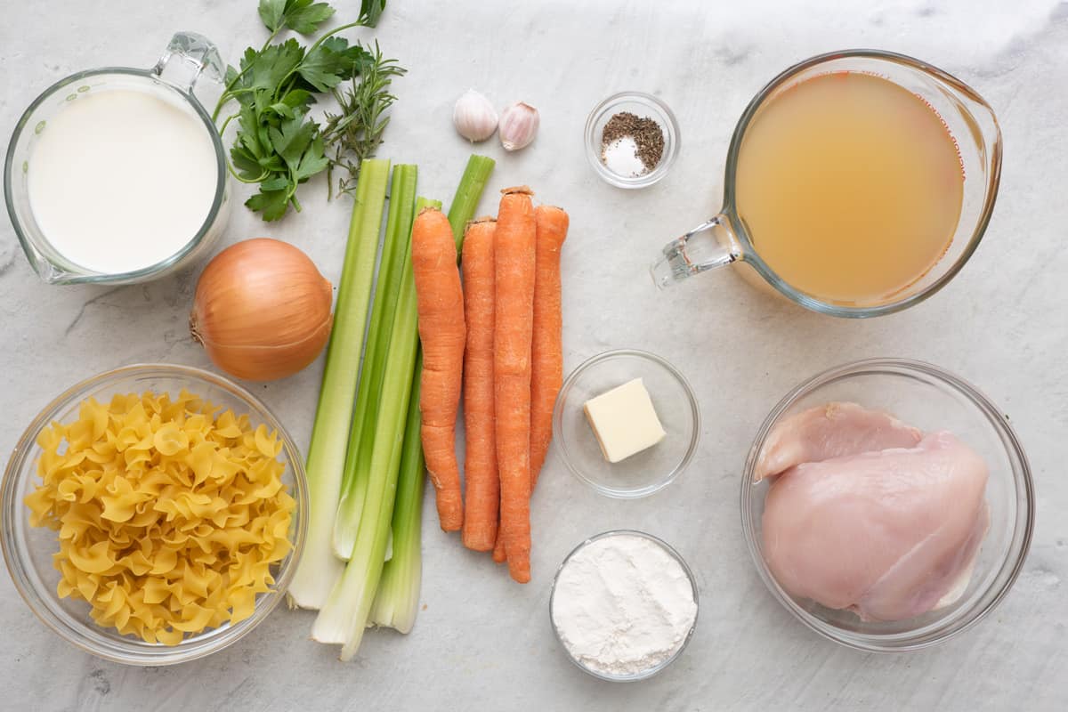 Ingredients for recipe: milk, parsley, onion, noodles, celery stalks, carrots, garlic, spices, butter, flour, broth, and chicken breast.