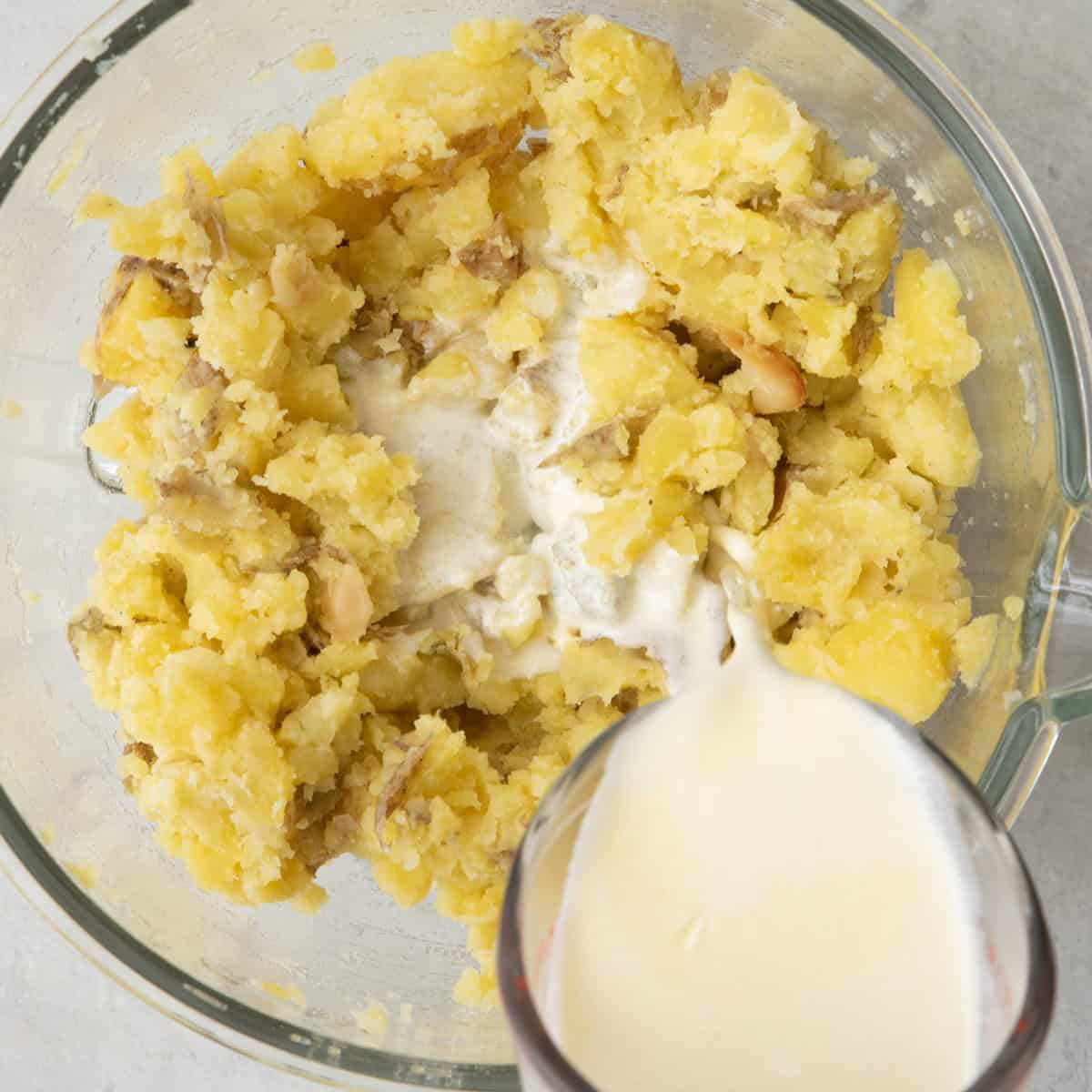 Sauce being poured into potatoes.