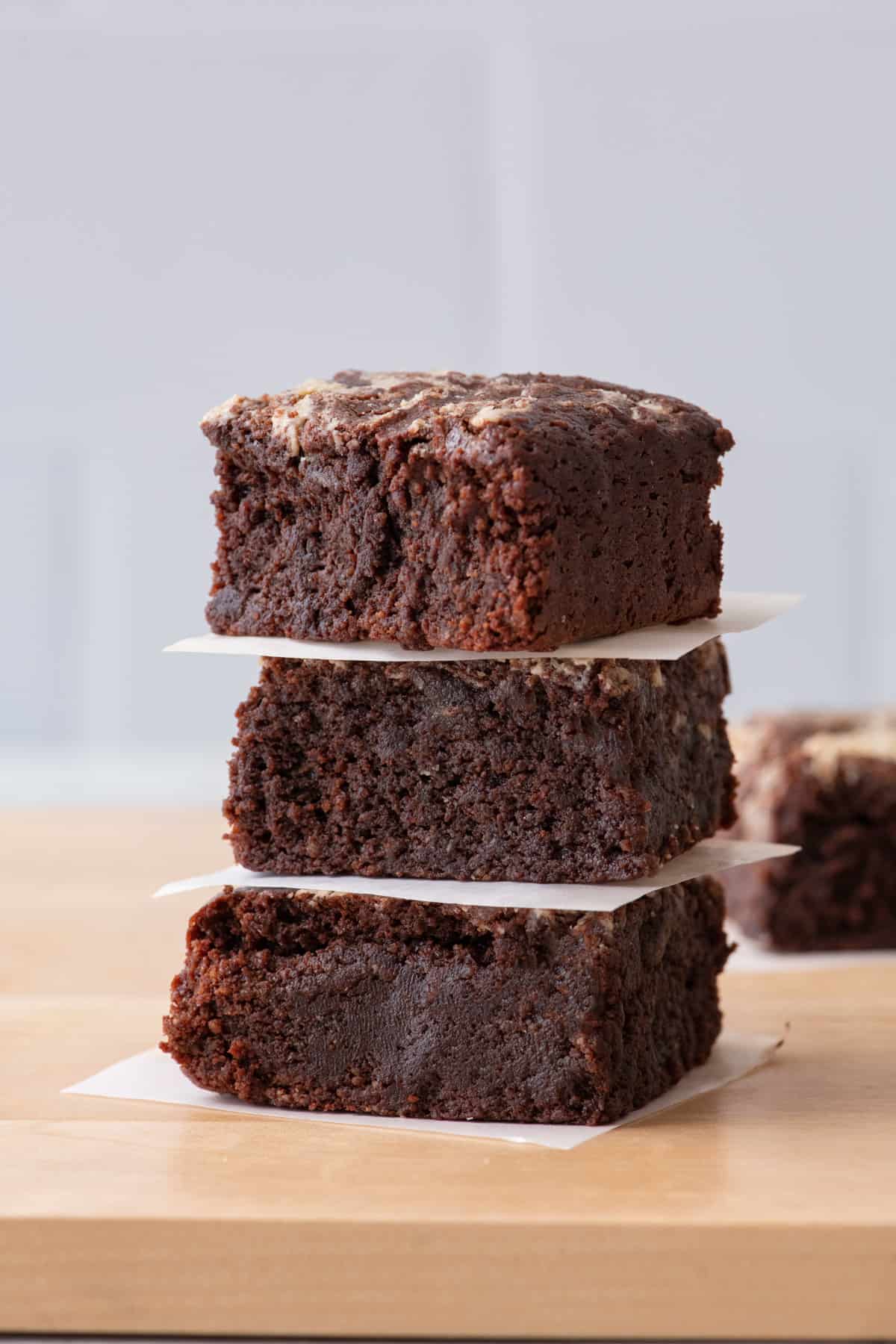 Stack of 3 brownies with a small square of parchment between each piece.