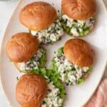 Turkey salad sandwiches stacked on a small serving plate/bowl with sandwiches hanging over the edges.