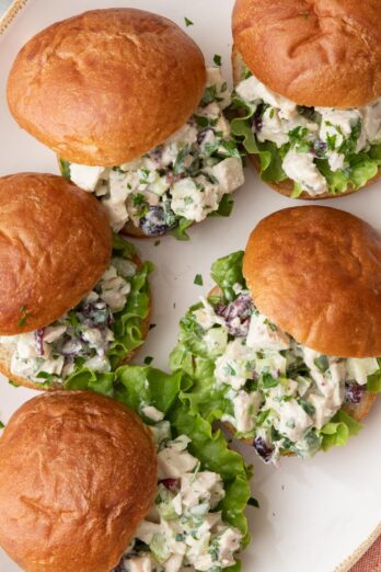 Turkey salad sandwiches stacked on a small serving plate/bowl with sandwiches hanging over the edges.