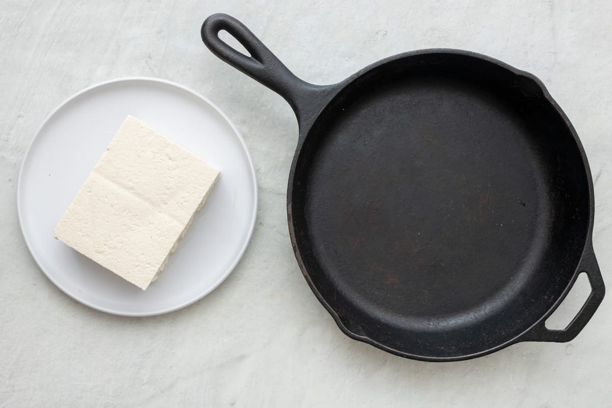 Block of tofu and a cast iron pan next to eachother.