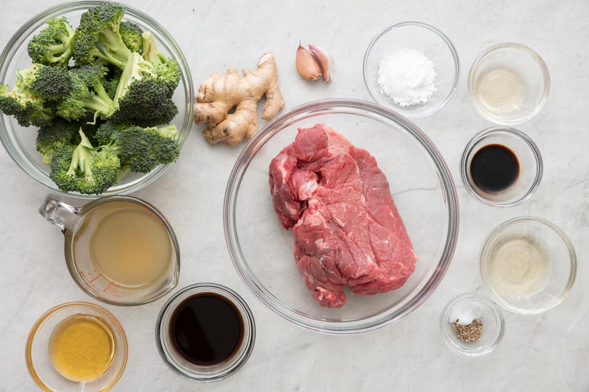 Ingredients for recipe in individual bowls: broccoli florets, broth, honey, soy sauce, ginger root, garlic cloves, beef, cornstarch, mirin, soy sauce, rice wine vinegar, salt and pepper.
