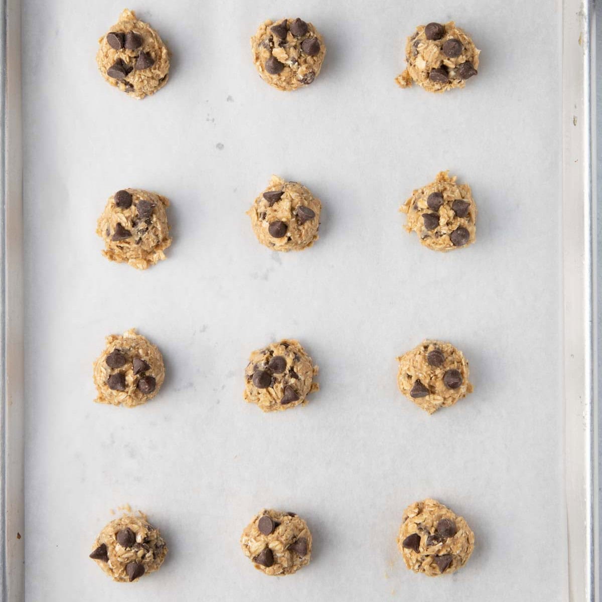 Rounds of cookie dough on parchment-lined baking sheet.