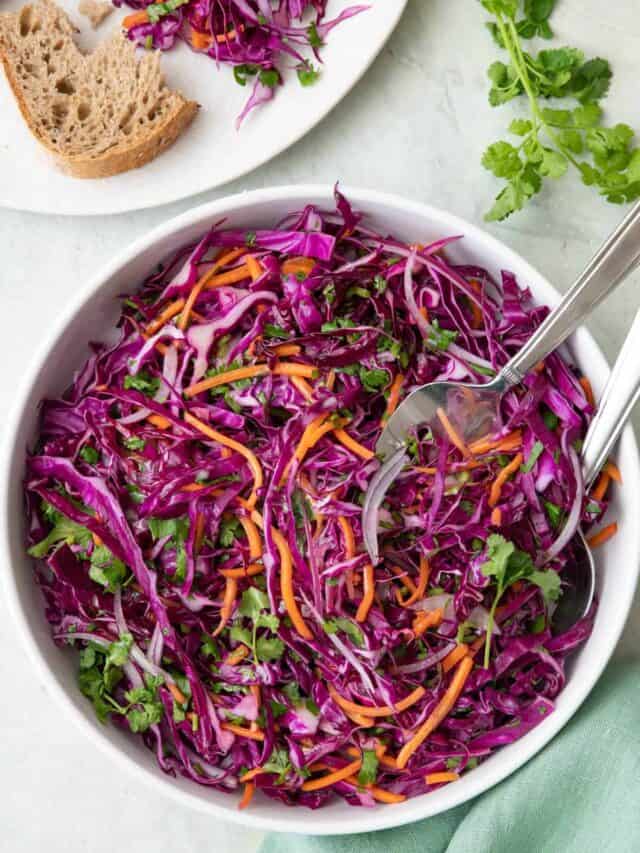 Large bowl of red cabbage slaw with serving set dipped inside.
