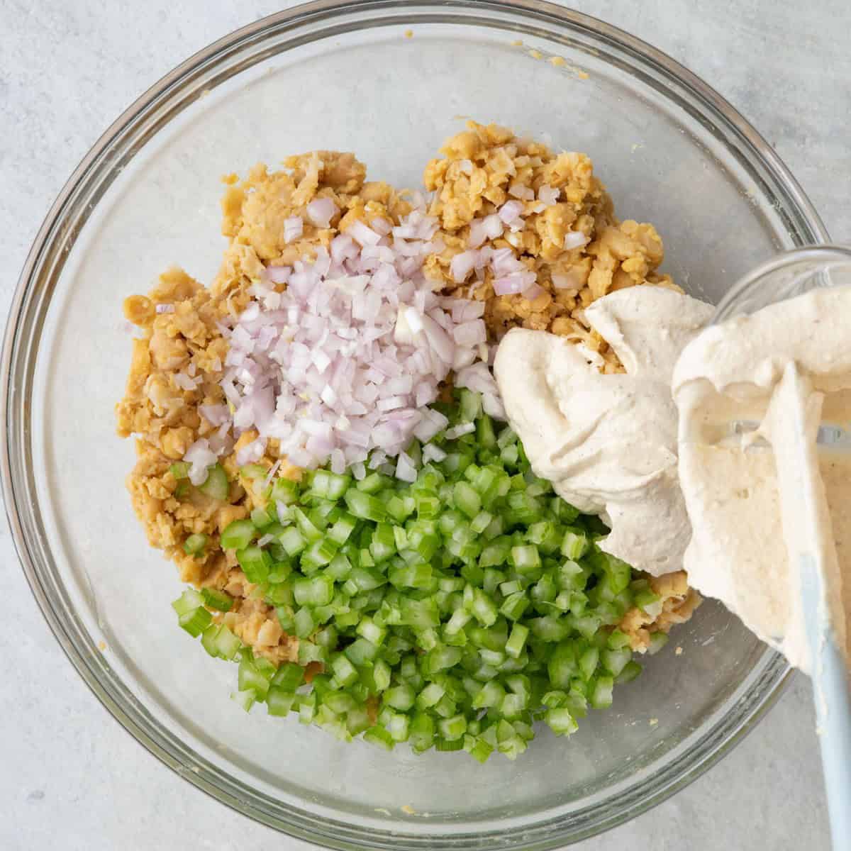 Pouring bowl of mixed dressing on top of the bowl.
